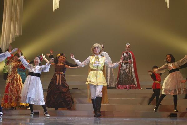 王子役の女性が手を広げて舞台に立っている写真