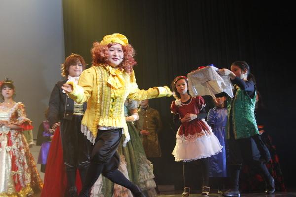 黄色い服を着た女性が手を広げてひょうきんに踊っている写真