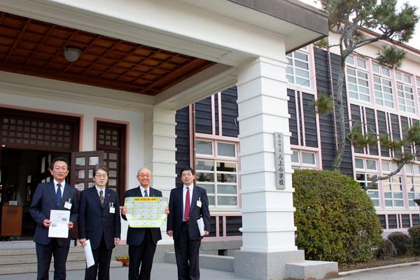 感謝状を持った市長達が校舎の前で記念撮影している写真