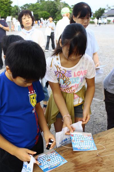 ラジオ体操カードにハンコを押す男の子と女の子の写真
