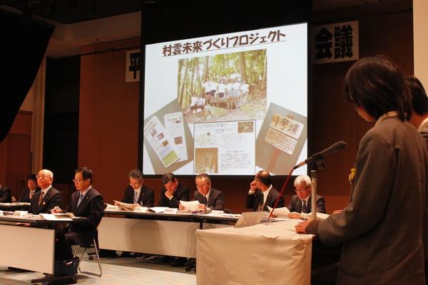 村雲未来づくりプロジェクトをスクリーンで写し、紹介する小学生と来賓の方が聞いている写真