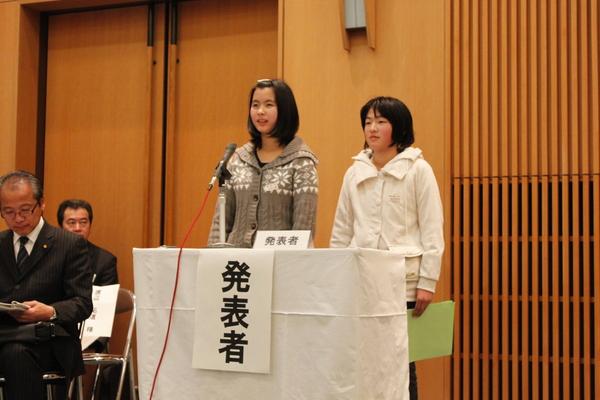 発表者と書かれた台の上にマイクが置かれていて、2人の女子児童が発表をしている写真