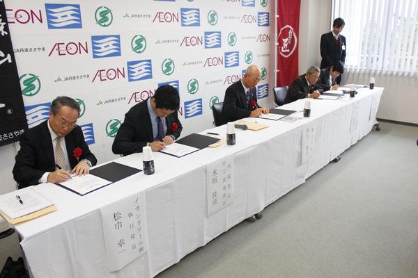 スーツの男性4名と市長が署名をしている写真