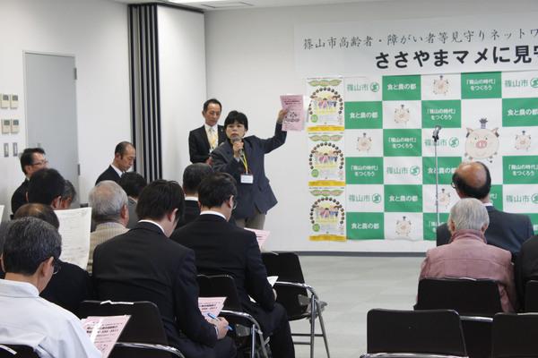 女性の方が資料を見ながら「ささやまマメに見守り隊」の方に説明している写真