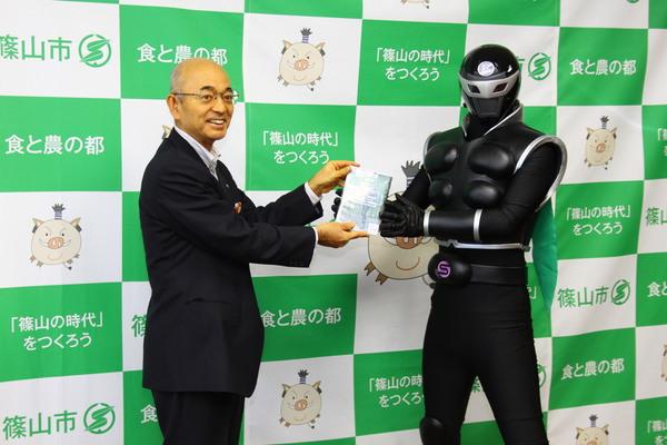 ササグローから公式テーマソングCDを市長に直接手渡している写真