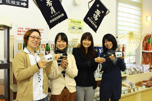 お土産屋さんの前で日本酒をお酌している人とお猪口を持っている女性4名の写真