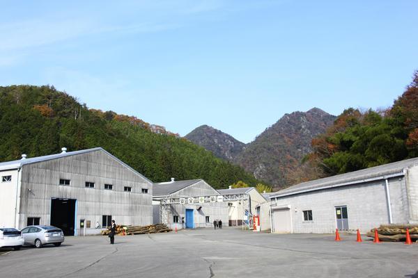 山野前に灰色の大きな倉庫が4棟立っている写真