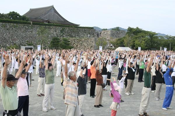 両手を上にあげている沢山の老若男女の写真