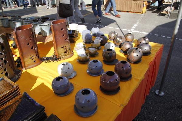 黄色いテーブルクロスの上に色々な形の丹波焼が飾ってある写真