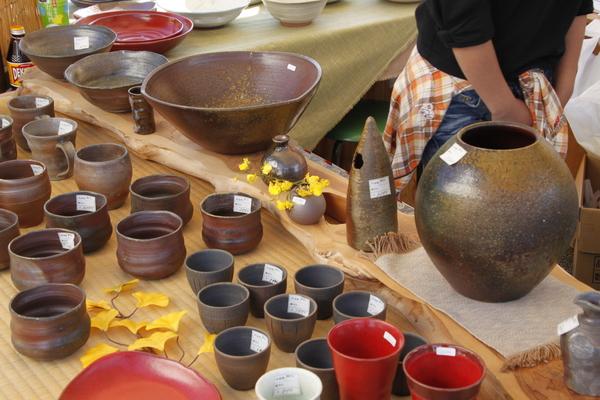 台の上には大きな壺や小さい様々な形の丹波焼が飾られている写真