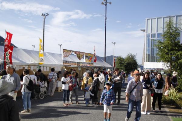 たくさんのお店のテントが立ち並び、周りでは大勢の人が歩いている写真