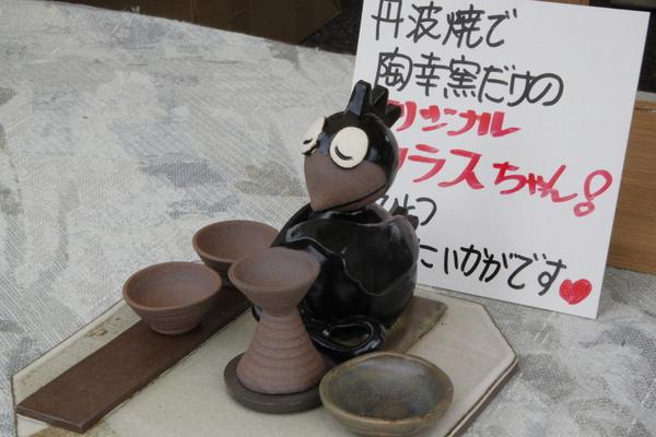 置物のカラスが飾られ、「オリジナルカラスちゃん！いかがですかと」書かれた紙が添えられている写真