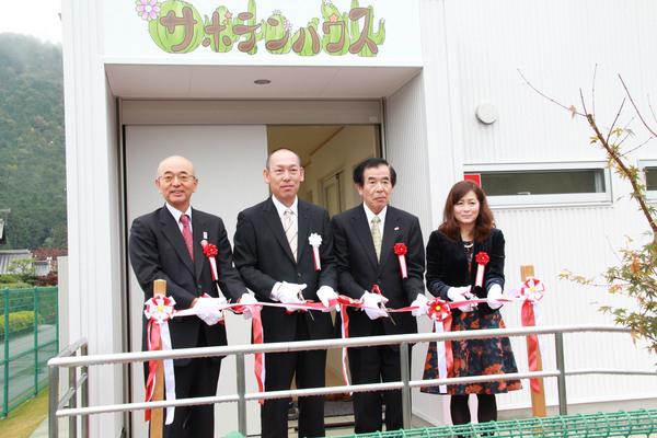 保育施設のサボテンハウスの前で、テープカットをする、市長、降矢社長、スーツの男性、チャイルドハートの木田さんの写真