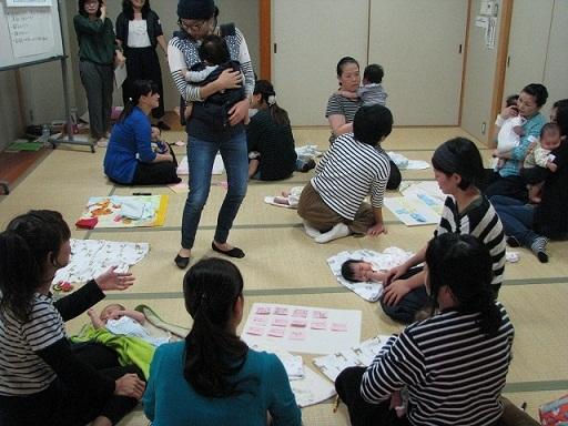 お母さん達が赤ちゃんを抱っこしたり、バスタオルに寝かせたりと赤ちゃんの様子を見ながら、談笑している様子の写真