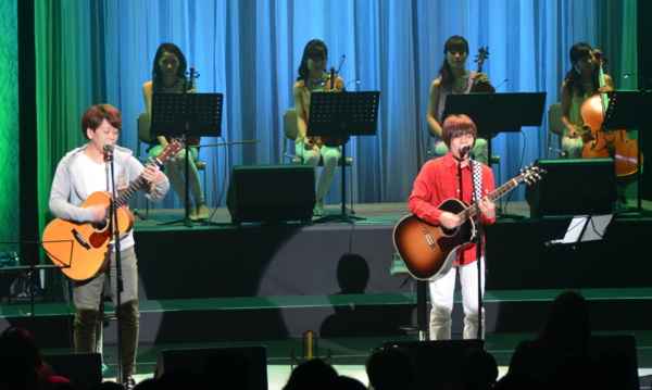 兄弟デュオ「ちめいど」の2人がギターを弾きながら歌を歌っている写真