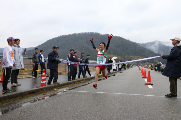 ゴールテープを切る寸前の、両手を上げて喜んでる男性ランナーの写真