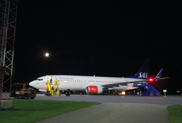 辺りが暗く月がみえるエステルスンド空港に飛行機が到着している写真