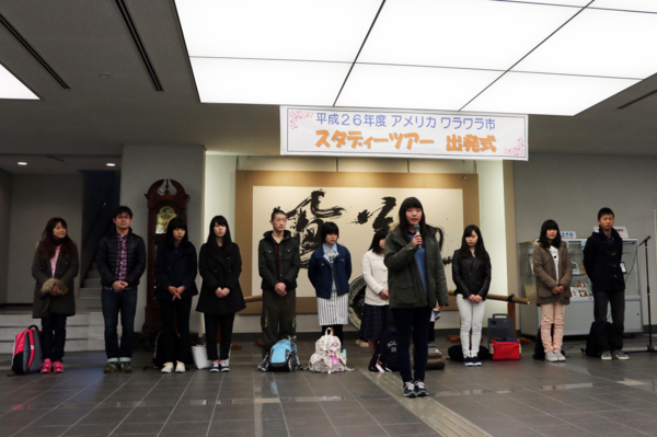 スタディーツアー出発式と張られた幕の下で代表の女の子がお話ししている写真