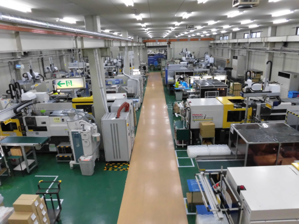 真ん中が通路となっており通路をはさんでたくさん機械が並んでいる工場内の写真