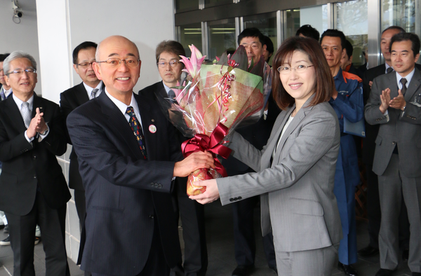 市役所庁舎前で女性職員から花束を受け取っている市長の初登庁の写真