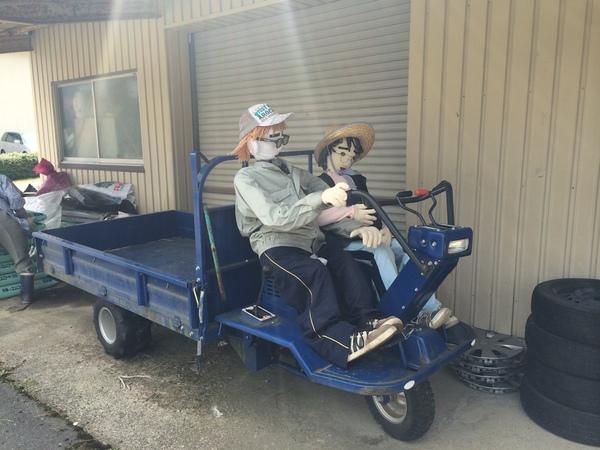 トラックの運転席と助手席にすわるかかしの人形の写真