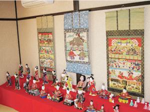 2列に並べられたひな祭りの人形と、その後ろに掛けられた掛け軸の写真