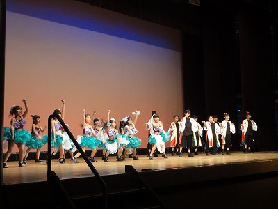 舞台で、衣装と法被を着た女の子たちが躍っている写真