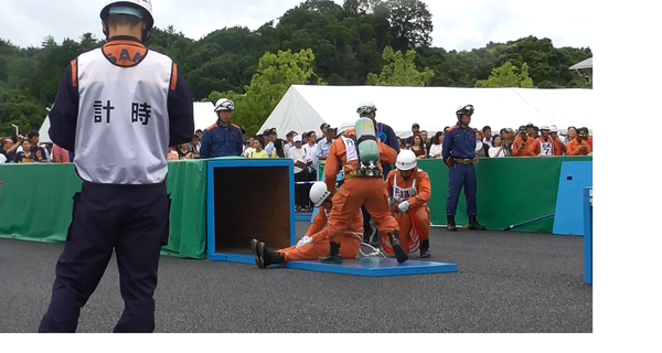 消防救助技術大会で技術者が救助者のロープの紐をほどいている作業を一人が計時している写真