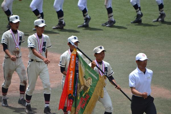 篠山鳳鳴高校の野球部主将が優勝旗を持ってみんなと行進している写真