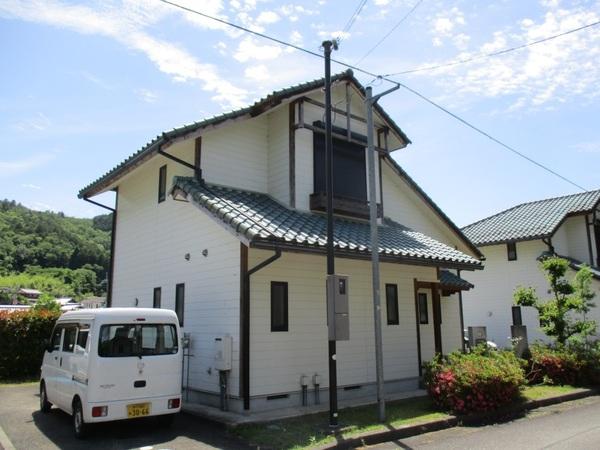 しゃくなげ団地の白い2階建ての家の横に白い軽ボックスカーが停車している写真