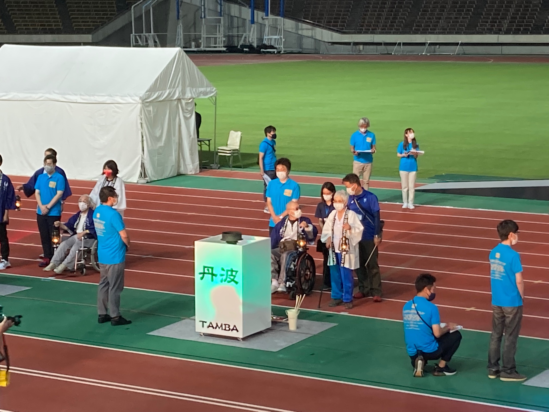 丹波と書かれた台が設置されており、聖火を灯すために関係者が囲んでいる