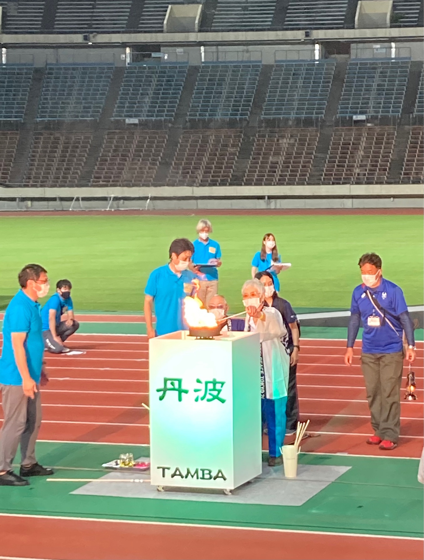 丹波と書かれた台に女性が聖火をともしている