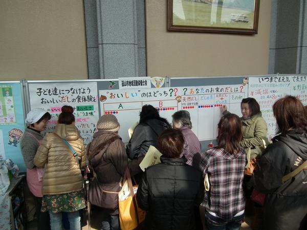 地域活動栄養士会のパネル展示コーナーを見ている女性たちの写真