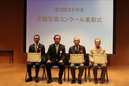 第3回ささやま景観写真コンクール表彰式のスライド前に座っている男性4名の写真
