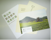 篠山市創造都市推進計画の書類と篠山の山並みと緑豊かな風景の写真がのっていいる冊子の写真