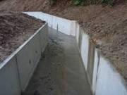 両脇は土が高く積まれており、コンクリートで作られてた水路が写っている写真