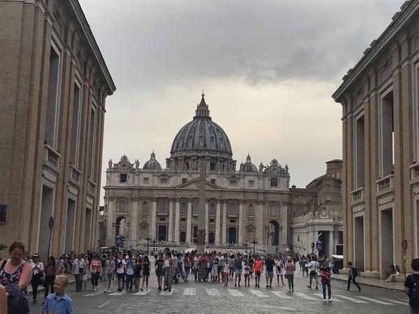 イタリアの美しいグレーのお城のような建築物の前にたくさんの人達が集まっている写真