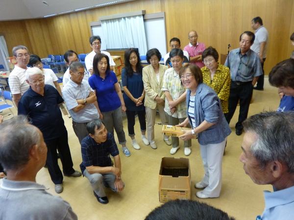 笑顔で箱を持っている講師の黒谷 静佳さんの足元に段ボールが置いてあり、黒谷 静佳さんを囲い、話を聞いているセミナー参加者の写真
