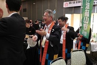 法被を着た男性たちが立って笑顔で踊っている写真