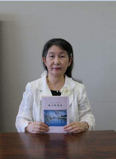 刊行された郷土史「城下町篠山」を手に持っている梶村幸子さんの記念写真