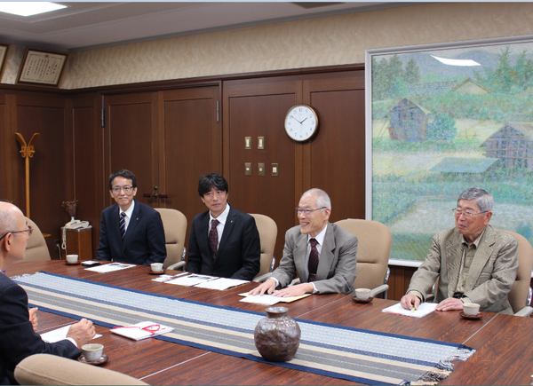 4名のスーツを着た男性達が市長の向かいに座っている写真