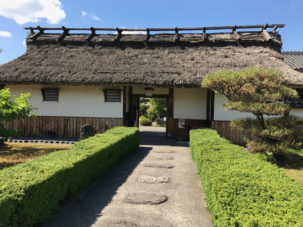 白い壁とわらの屋根の青山歴史村の入り口の外観写真