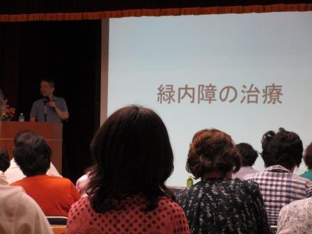 男性の方がスクリーンで写された緑内障の治療を説明されてる写真