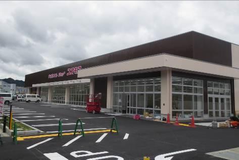 茶色と白の外壁に赤い文字の看板の建設途中のコスモスの建物の写真