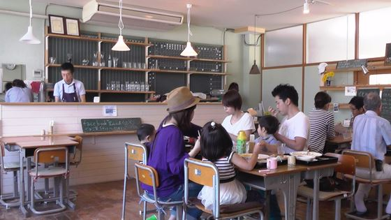 閉校した学校の教室で、ご飯を食べている家族や、お客さんの写真