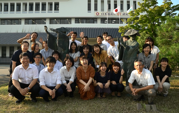 丹波篠山ふるさと大使の森田 まり子さんと、職員が笑顔で銅像の間に座っている集合写真