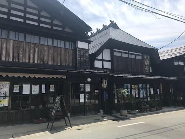 古い大きな建物ははお店で、お店の外には看板が置いていある写真