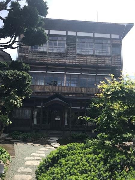 大きな古い2階建ての家で緑に囲まれている写真
