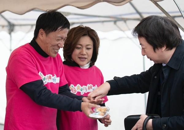 テントの中で七井 貴行さん川崎 美千江さんがお客さんにお菓子を販売している写真