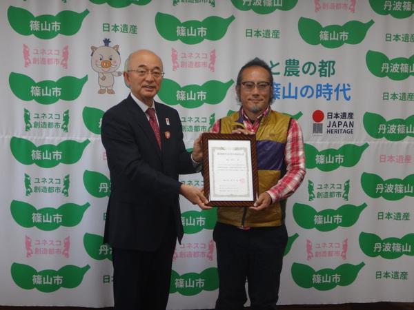 森田 耕司さんと市長が額に入った農業経営改善計画認定書を一緒に持ち、記念撮影している写真